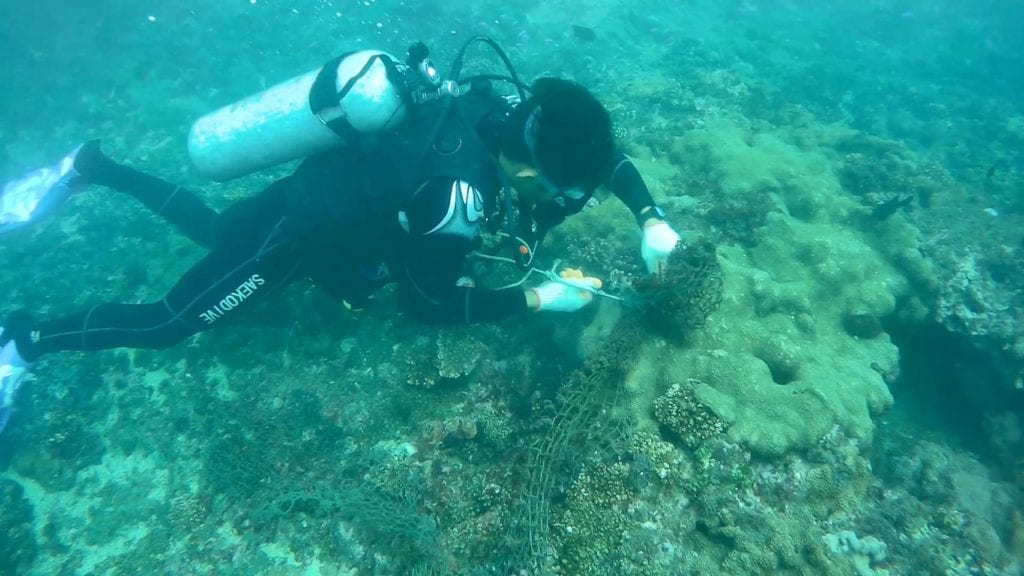 漁民潛入海底清理漁網勾住的漁具。