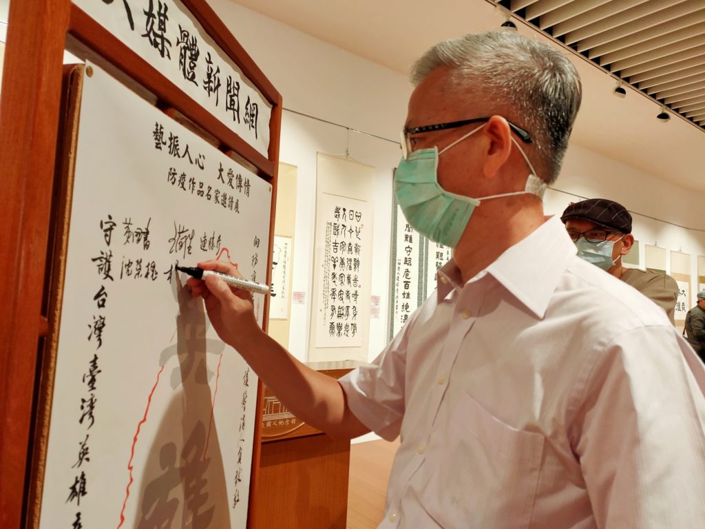 知名書法家楊旭堂在防疫作品祈福板上,向防疫臺灣英雄簽名致敬。(圖/詹美絨 攝)