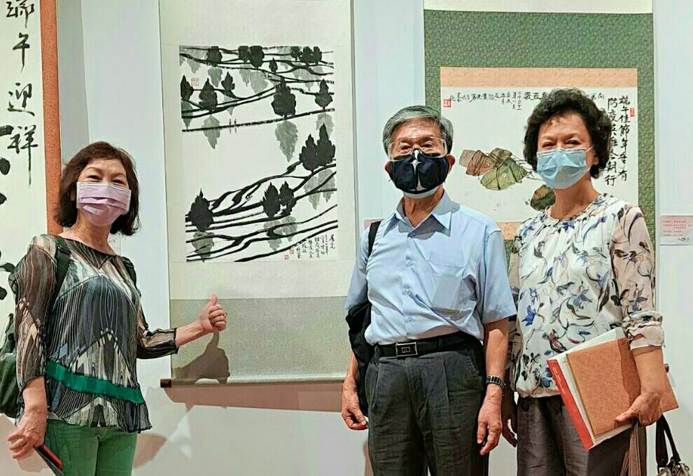 畫家林菲滿老師(左起)羅振賢教授與孫美茹老師展場相見歡,後為羅振賢教授之作品「晨光」。(圖/詹美絨 攝)