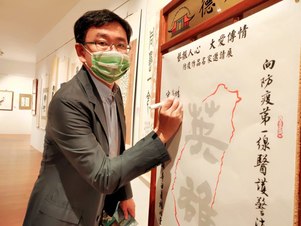 參展藝術家的立法委員黃國書,在防疫祈福卡前簽名留念。(圖/詹美絨 攝)