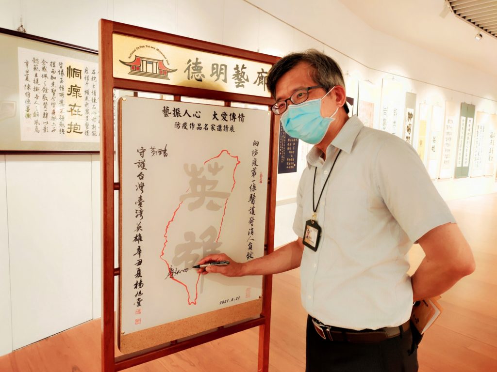 國立歷史博物館館長廖新田,特別撰寫一幅防疫書法作品參展,並開心的在臺灣英雄祈福卡上簽名。(圖/詹美絨 攝)