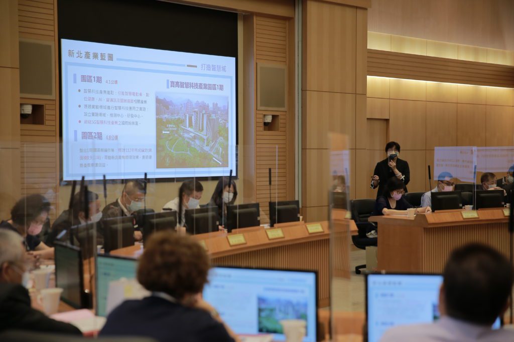 經發局長何怡明(右側站立者)於會中說明疫情期間新北防疫紓困作為、振興方案及疫後產業發展策略