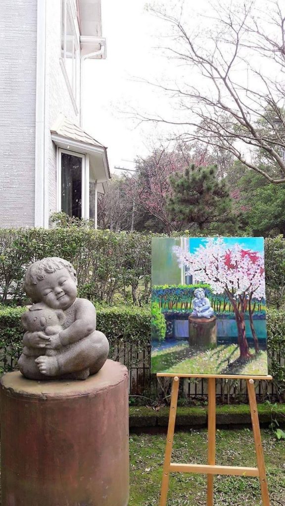 王婷儀選擇將父親作品《甜心寶貝》入畫,結合園區內櫻花美景為創作題材,以熟悉的畫筆表達對父親之景仰,及父親視女兒為至寶之情。(王詩鵑提供)