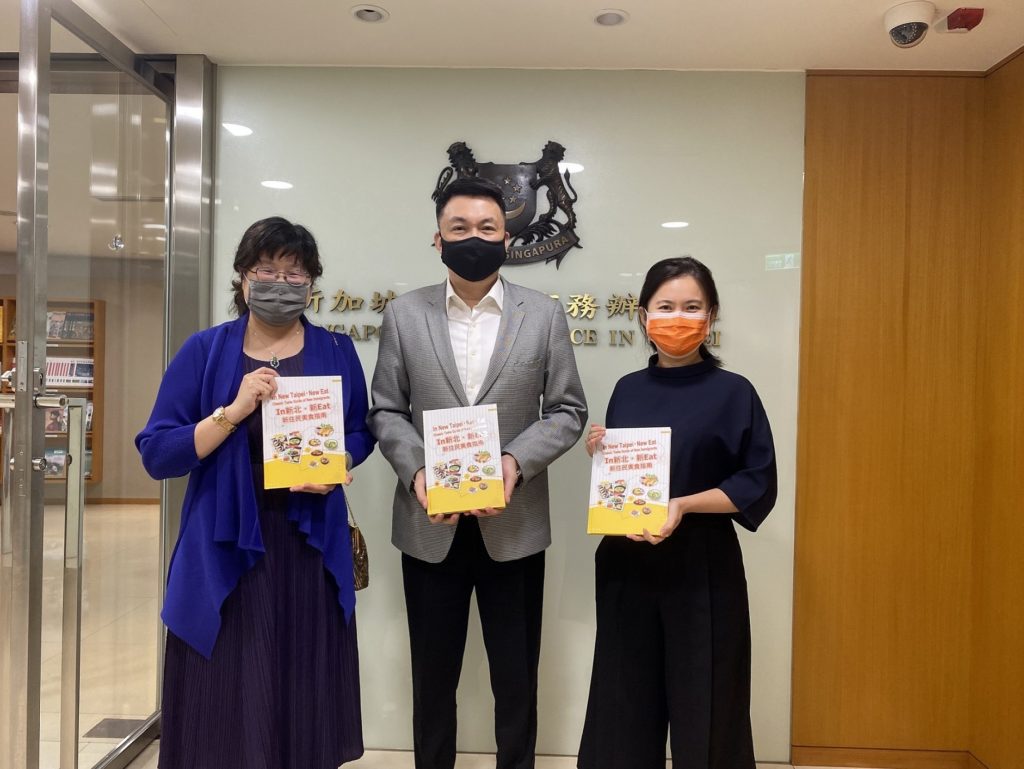 ▲經發局長何怡明(左)拜訪新加坡駐台北商務辦事處，向新加坡駐台代表葉偉傑(中)、黃筱涵主任(右)分享在新北市的異國美食料理，以及「新北嚴選」計畫。〈經發局提供〉
