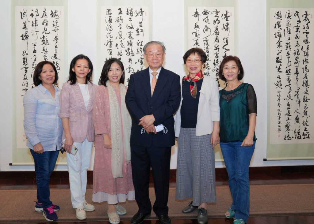 多位女書法家與張炳煌教授(中)合影,後為張教授之紅樓夢書體作品。(記者 辛澎祥/攝)