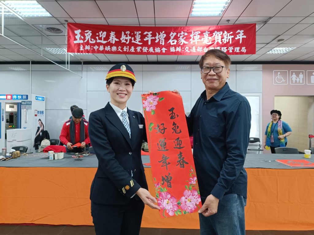兔年新運之際，策畫寫春聯活動的協會理事長辛澎祥（右），特別將別緻的兔年創意春聯贈送給臺鐵台北站，由站長胡詠芝代表接受。（記者 陳安婷/攝）