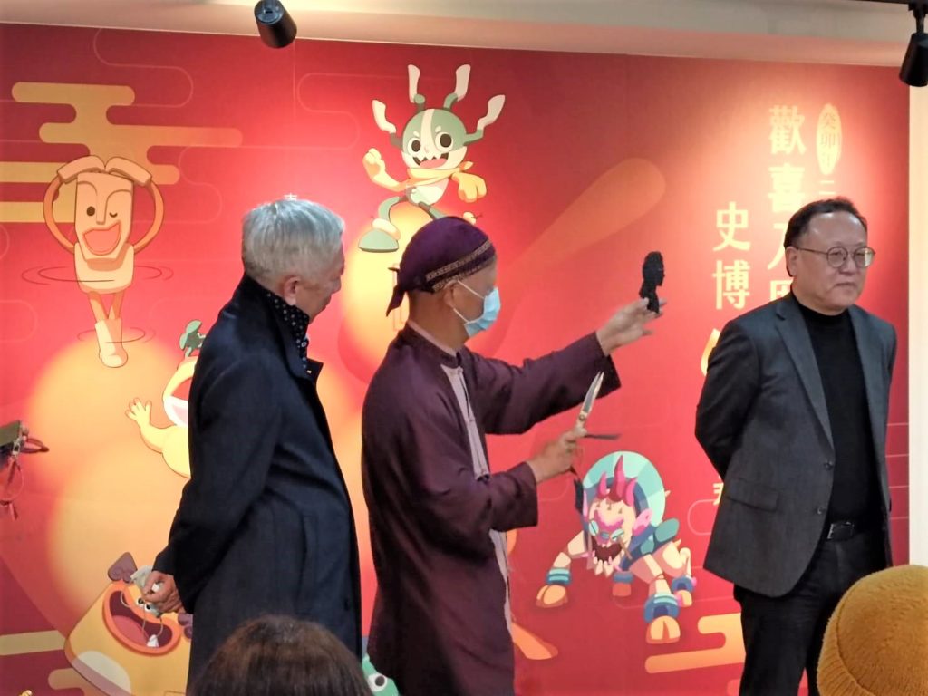 ▲剪紙藝術家陳茂泉(中)為文化部長史哲剪影時,史博館館長梁永斐一旁贊揚其高超技藝。(記者 陳安婷/攝)