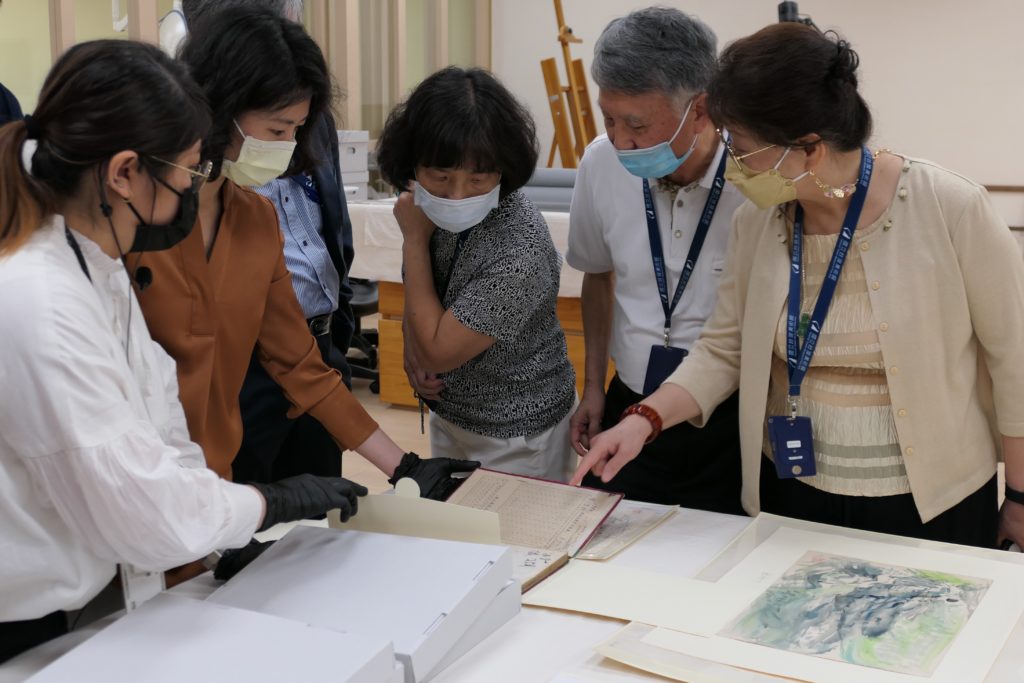 修復師向洪瑞麟家族代表洪柏信與張芳錱伉儷(右1及右2)，及白雪蘭女士(中)解說作品保存維護與整飭情形。（圖/國美館提供）