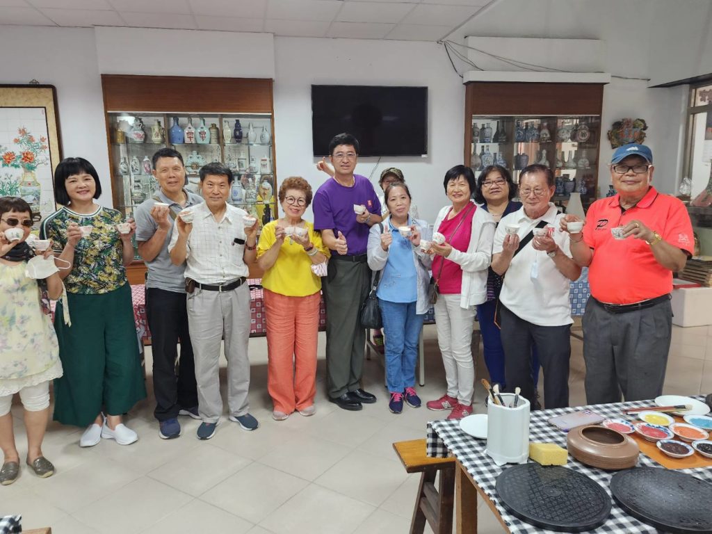 ▲何桂泉廠長(左六)與全體書畫家們完成陶杯彩繪後,開心合影留念。(記者 辛澎祥/攝)