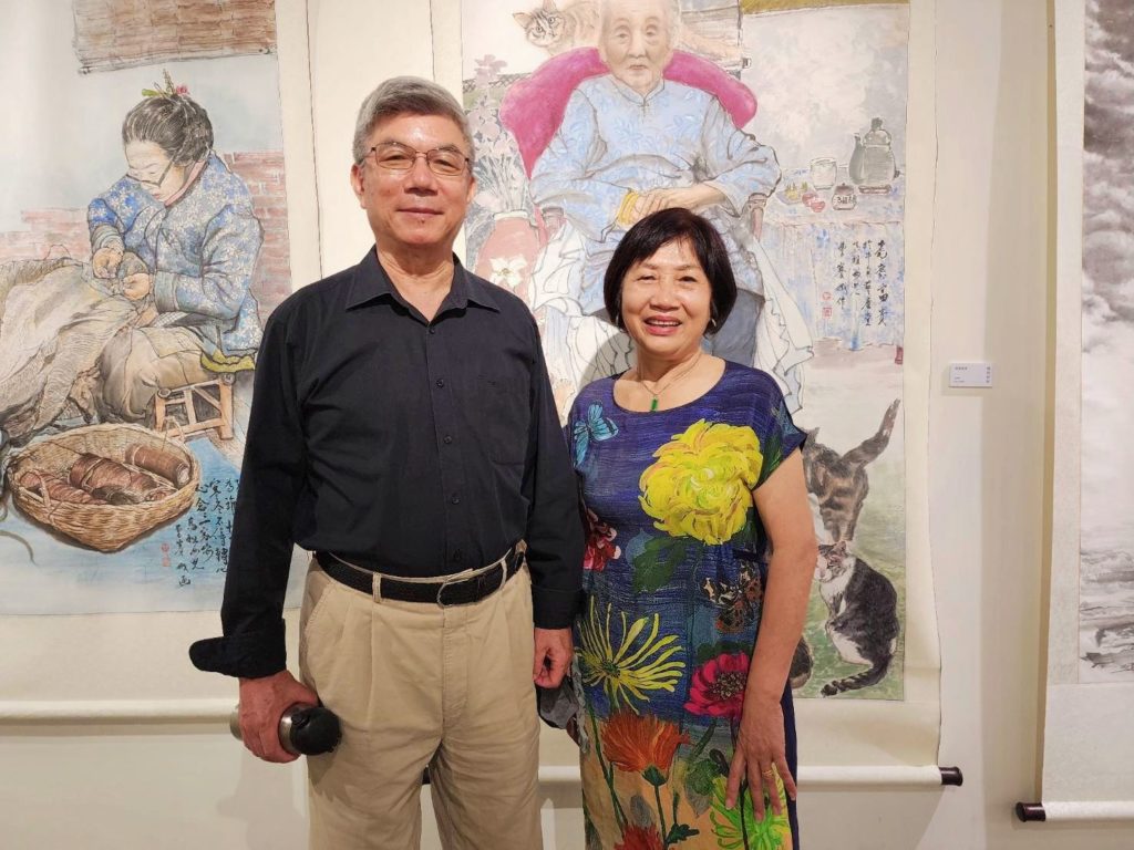 ▲陳合成教授(左)與曹賽娥老師有小學同學的深厚情誼,兩人在展場開心合影留念。後為曹賽娥的作品,其人物描繪維妙維肖。(記者 辛澎祥/攝)