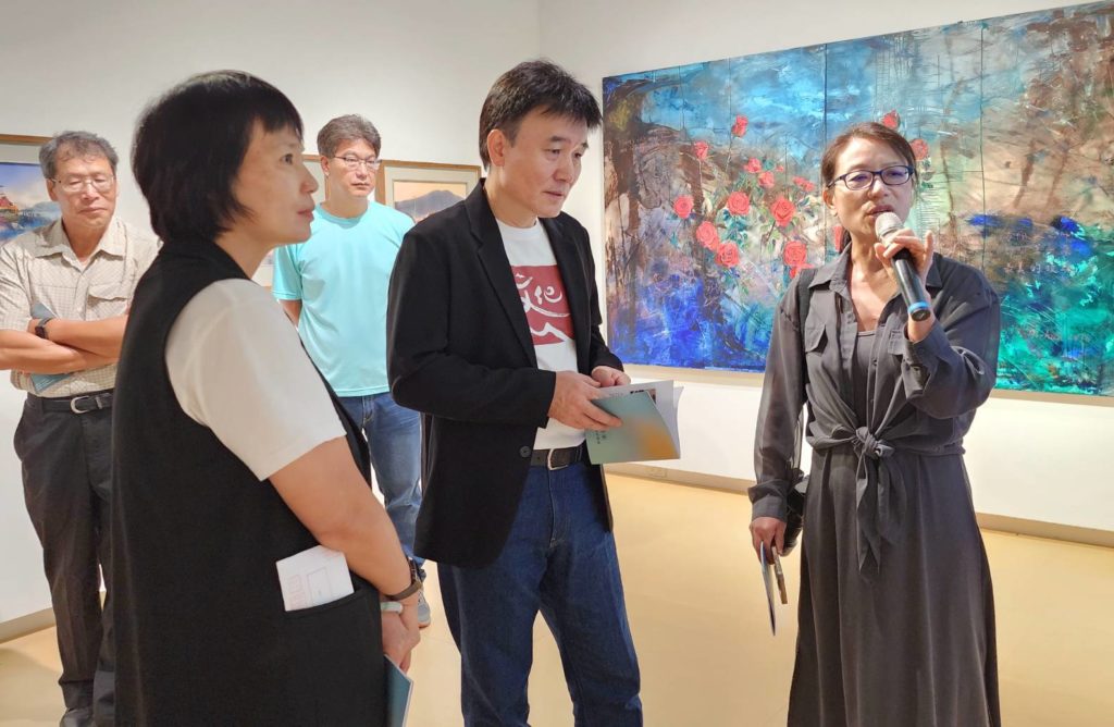 ▲文化處處長吳曉雲(左起)與副縣長陳冠人聆聽馬祖旅台藝術家畫會會長鄭愛華(右)所進行作品導覽,場面熱烈。(記者 辛澎祥/攝)