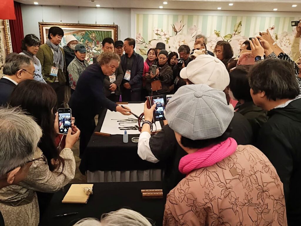 ▲韓國大田大學教授李周炯(中)勁筆寫下「淵遠流長」大字,受到與會者的熱烈圍觀與喝采。(記者 辛澎祥/攝)