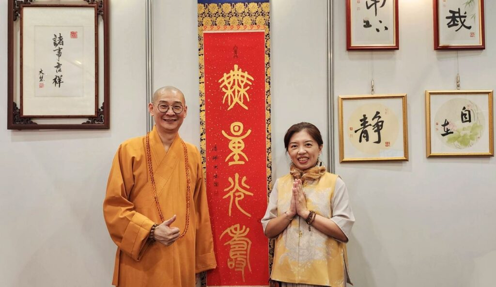 ▲由潘珮君老師（右）所書寫的篆體佛語「無量光壽」，主旨是為了慶祝佛誕節，該幅作品受到大慧法師的肯定與讚賞。（記者 辛澎祥/攝）