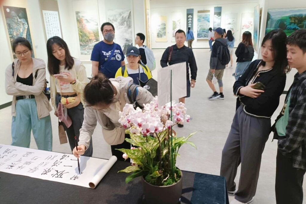 ▲外籍遊客來到展場聆賞作品，順勢毛筆簽名，顯得格外接地氣般的雅興。（記者 辛澎祥/攝）
