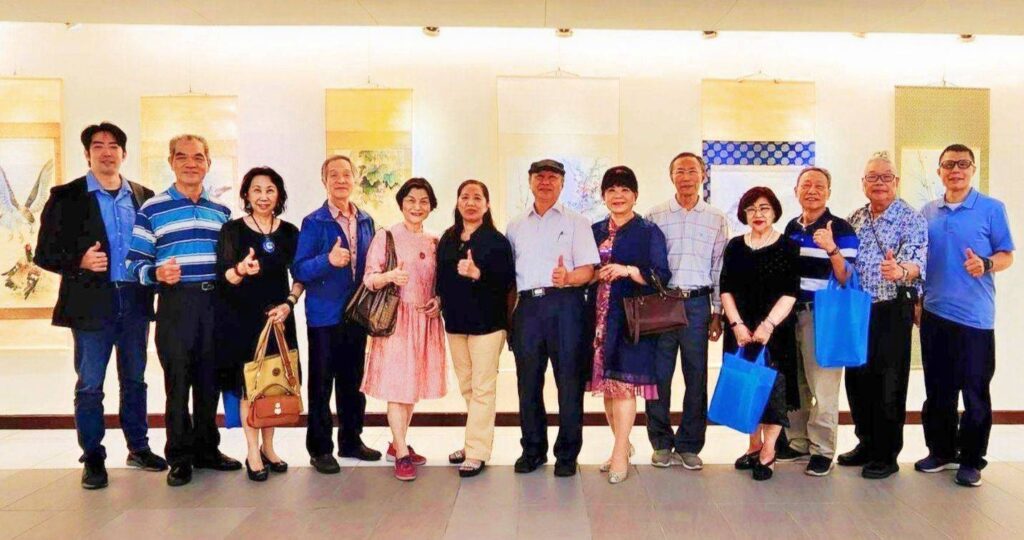▲參展藝術家在多幅作品前大合照,拍攝平正明亮,整體畫面呈現舒暢協調感。(圖/林淑珠 提供)