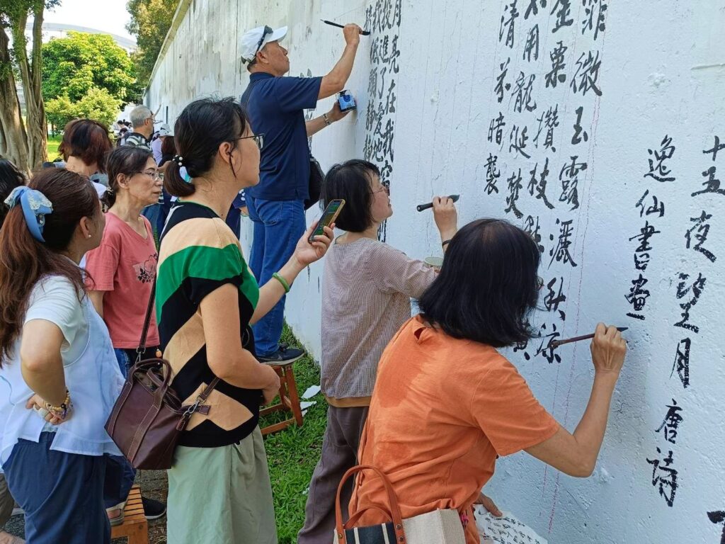 ▲知名女書法家也是書會領導人的連瑞芬老師(右二)專注壁書書寫,受到多人的圍觀駐足欣賞。(記者 辛澎祥/攝)