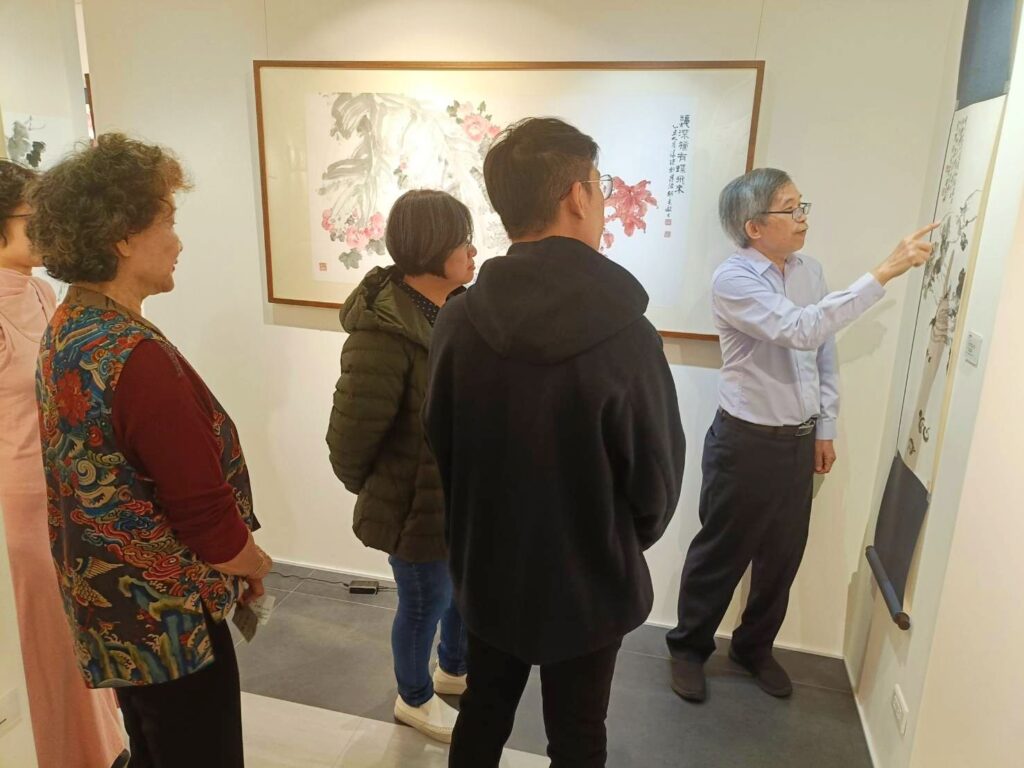 ▲廖新田教授(右)以胡克敏的畫作所展現傳統水墨畫的墨骨精神,強調胡克敏是寫意花卉的第一人,一筆定型的功力無人能及。(記者 辛澎祥/攝)