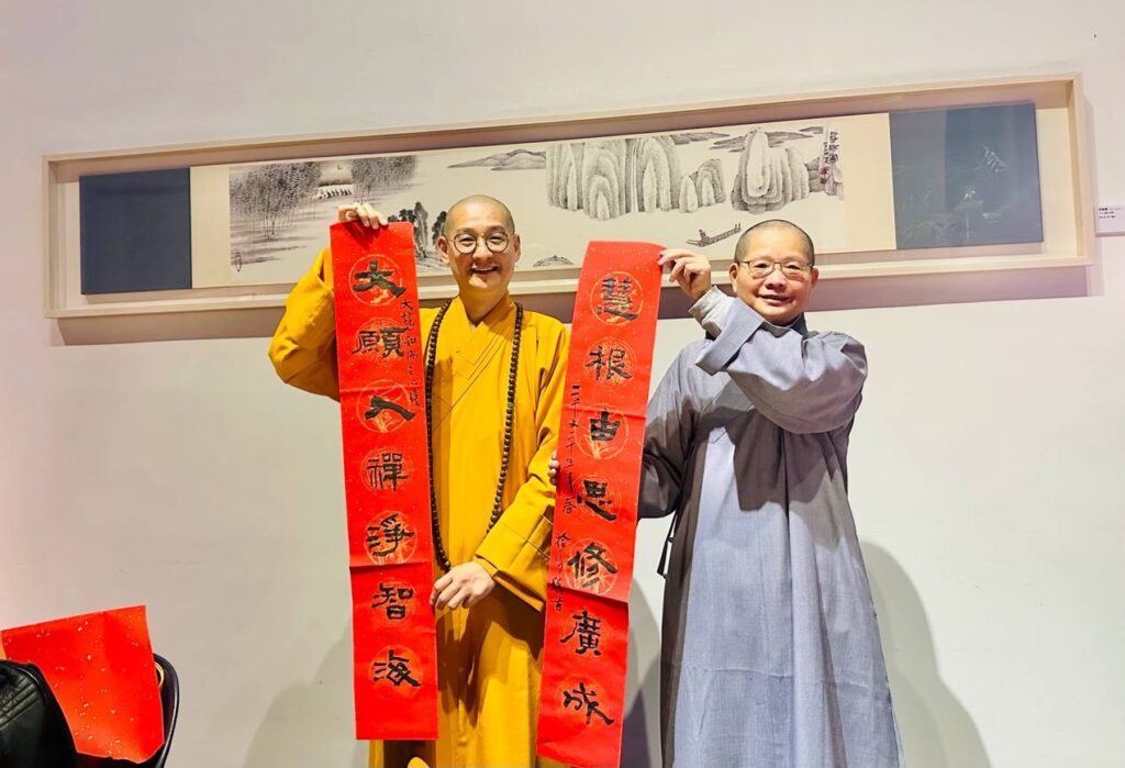 ▲拾得法師(右)現場作嵌字春聯贈送貴賓,左為大慧法師。(圖/陳耀姬 提供)