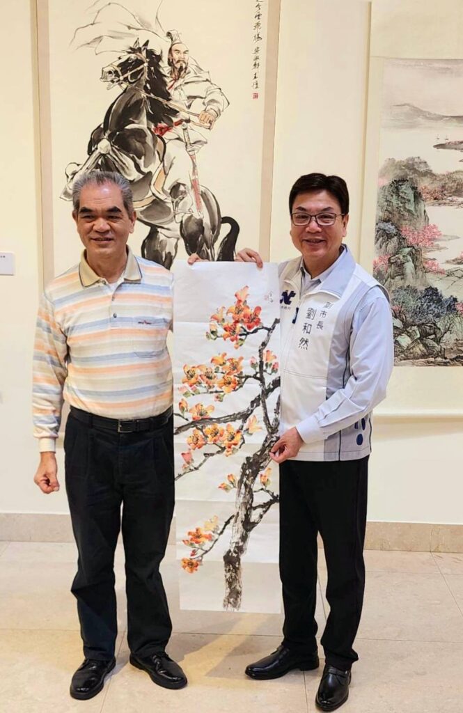 ▲協會副理事長陳金海（左）將所繪的水墨花卉作品贈送給新北市副市長劉和然，彰顯畫作所呈現的福壽綿延。（記者 辛澎祥/攝）
