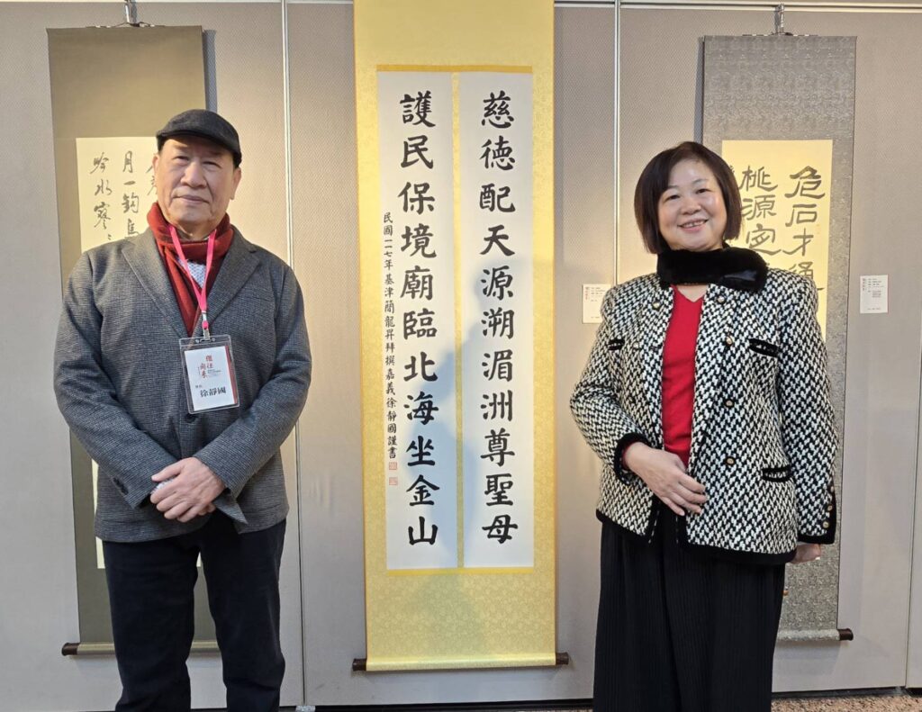 ▲傑閣書會會長徐靜國(左)與夫人在其楷書作品前合影,習書多年,筆鋒帶有豐富感情。(記者 辛澎祥/攝)