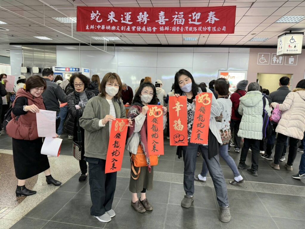 ▲來臺旅遊的日本朋友巧遇臺北車站書畫老師寫春聯活動，排隊索取後開心拿著剛出爐的春聯合影。（圖/大媒體新聞網 提供）