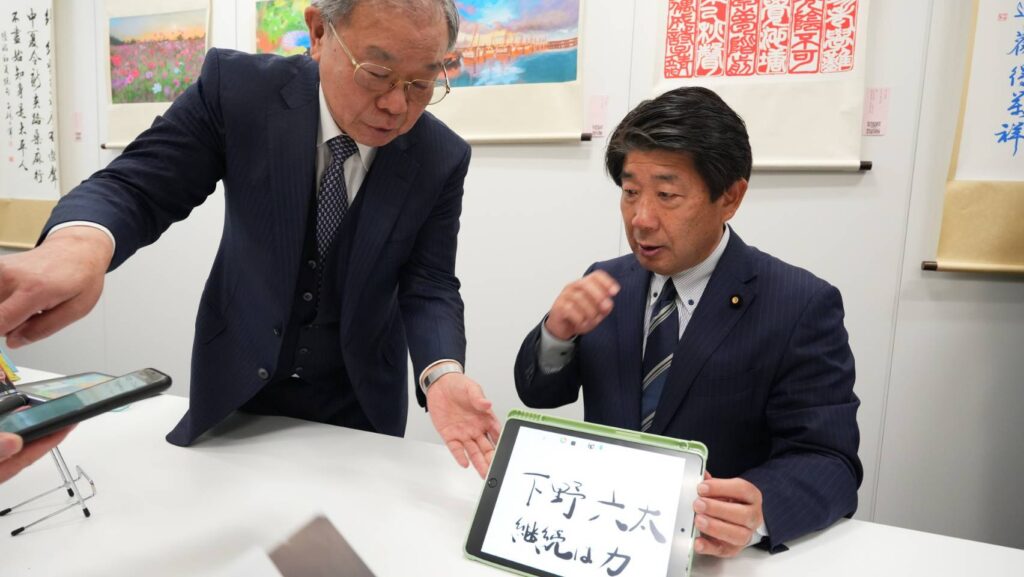 ▲張炳煌教授（左）向日本眾議員介紹智慧e筆的書法構成。（圖/文化部 提供）