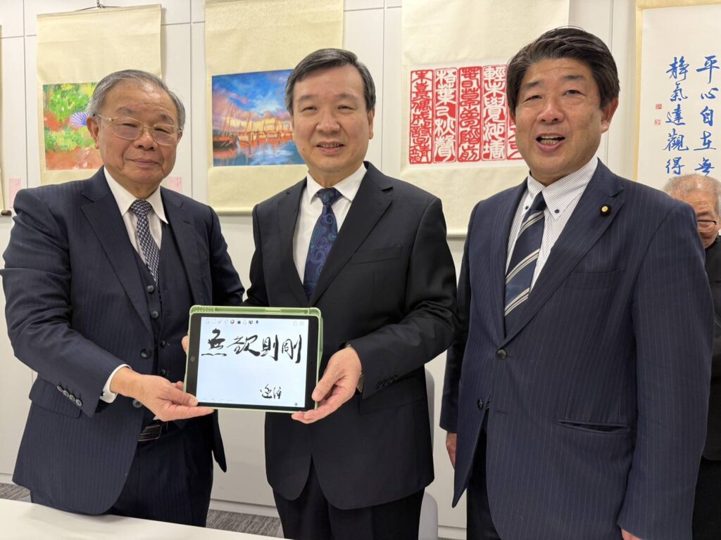 ▲張炳煌教授（左）指導臺灣駐日代表李逸洋（中）e筆寫下「無欲則剛」四字，顯得格外愉快。（圖/文化部 提供）