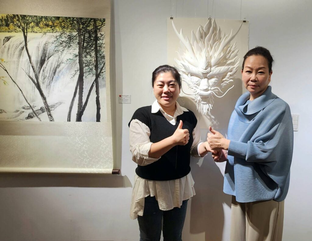 ▲中華畫筌美術協會理事長鄭娟娟（右）與製作紙藝作品的會員陳韶敏，在作品「活龍活現」前合影。（記者 辛澎祥/攝）