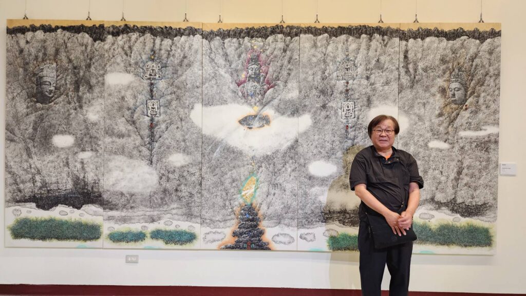 ▲臺灣美術院副院長李振明教授，以壯觀的五連屏水墨作品「眾神祐許的所在」展出，並在作品前開心留影。（記者 辛澎祥/攝）