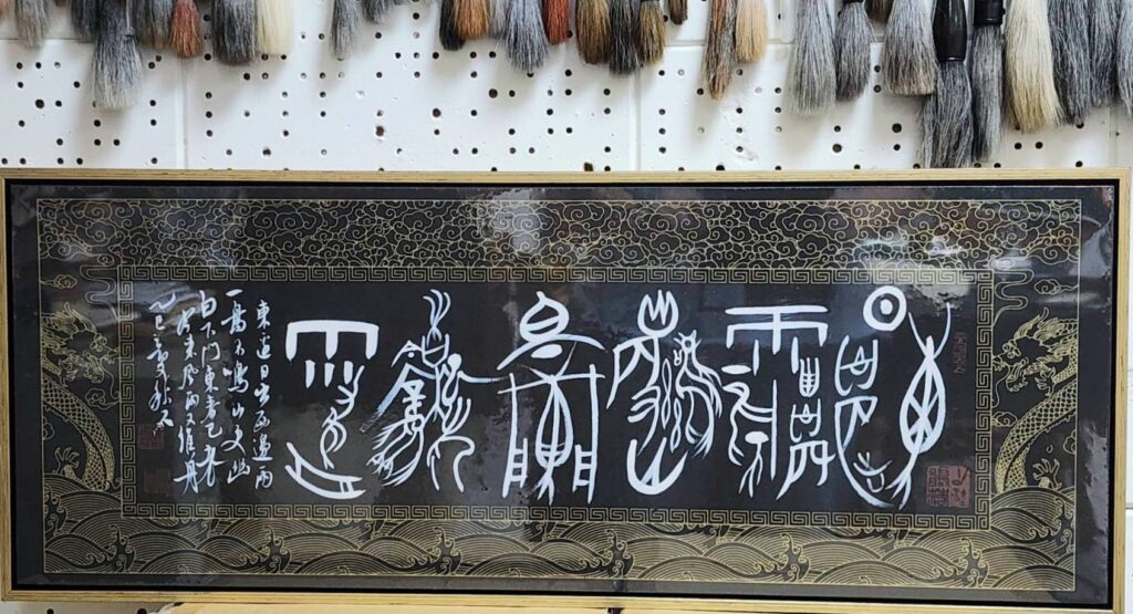 ▲施春茂教授以創意甲骨文書寫「東邊日出西邊雨 一鳥不鳴山更幽 白下門東春已老 今來風雨又催舟」可說是書藝轉化創新之作，十分傳神。（記者 辛澎祥/攝）