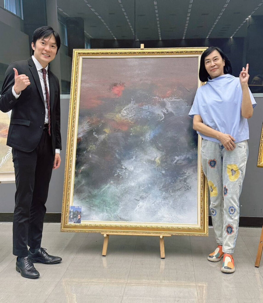 ▲台中市政府法制局局長李善植(左)與壹元書院院長賴慕芬於會場合影留念。後為新加坡知名油畫家黃意會大師的畫作,格外吸睛。(圖/賴慕芬 提供)