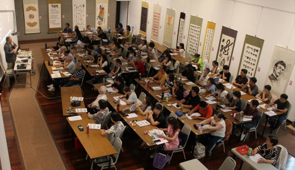 ▲在佈滿各書體的創作書藝作品環境中學習嶄新的書法課程與教育推廣內容，張炳煌教授（左）與學員們面對面從理論到實務進行交流探討，使研習書法教學成為熱門的藝文活動。（圖/張炳煌 提供）