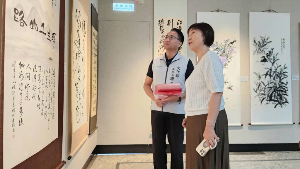 ▲何慶珍老師（右）所書寫的「浮生千山路」詩詞文體，並與唐連成副局長現場合唱，令人驚訝之餘卻也意外成為展場焦點。（記者 詹佳綺/攝）