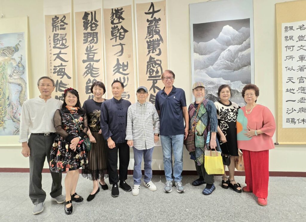 ▲知名書法家也是大岡藝術基金會董事長施春茂（左五）在他的四聯屏作品前與協會參展藝術家們開心合影留念。（記者 詹佳綺/攝）