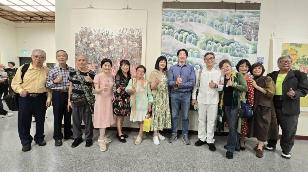 ▲協會參展藝術家在展場作品前開心合影，能透過展出機會與名家聯合交流展覽，覺得是難得的際遇。（記者 詹佳綺/攝）