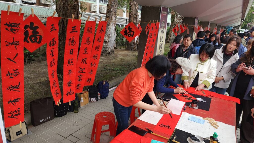 ▲中華民國書法教學研究學會理事長陳泱昭（中）率領會員老師們加入寫春聯行列，場面熱烈。（記者 詹佳綺/攝）