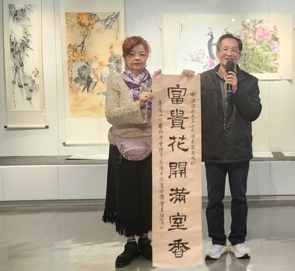 ▲基隆市水墨藝術學會理事長陳文永(右)出席開幕式,並將親寫書法作品以賀詞形式贈送給梁瑞琴老師,兩人並合影留念。(記者 詹佳綺/攝)