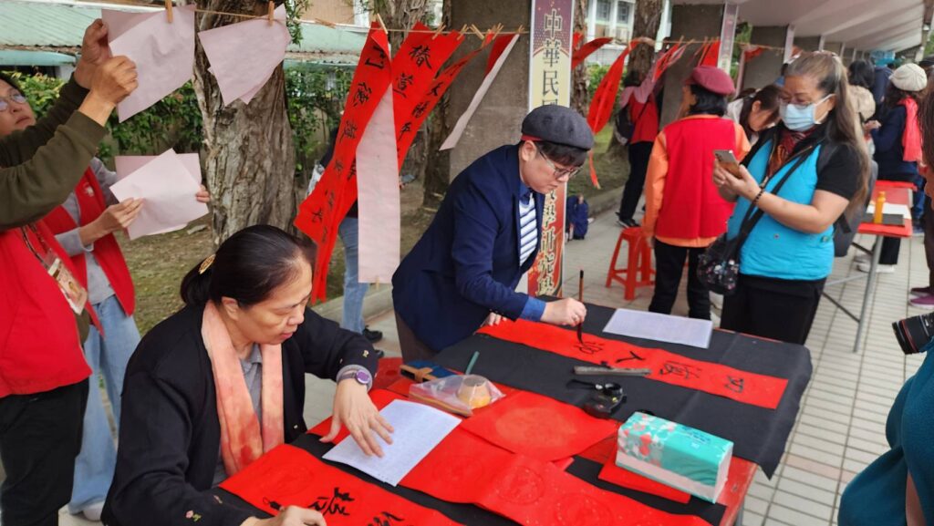 ▲中華民國標準草書學會理事長黃勻祺（左二立者）書寫春聯，架勢十足，引起民眾的關注。（記者 詹佳綺/攝）