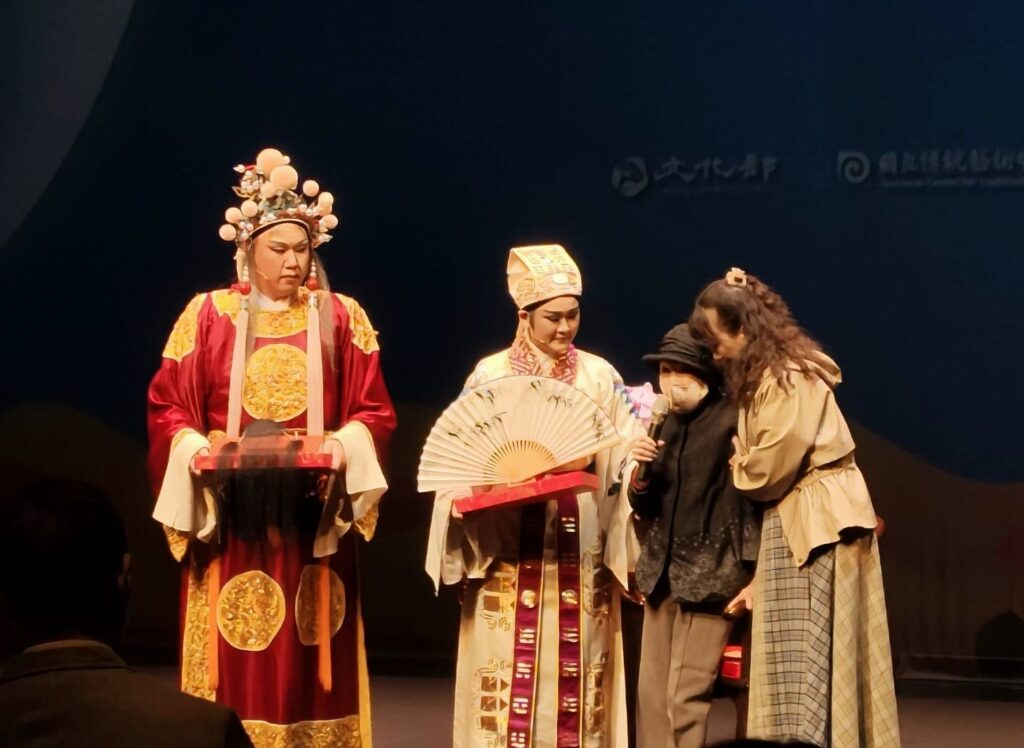 薪傳歌仔戲劇團藝術總監廖瓊枝（右二）以小生摺扇與老生髯口勉勵吳妍菲（左二）與鄭力榮（左一），諄諄教誨，場面感人。（記者 陳安婷/攝）