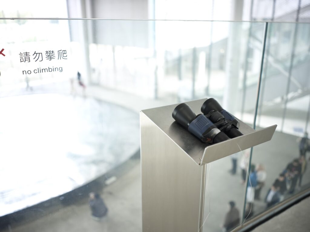 連接美術館與圖書館的二樓連通橋設有一支望遠鏡可俯瞰大廳人流，捕捉建築中流動的節奏。（圖/文化局提供）