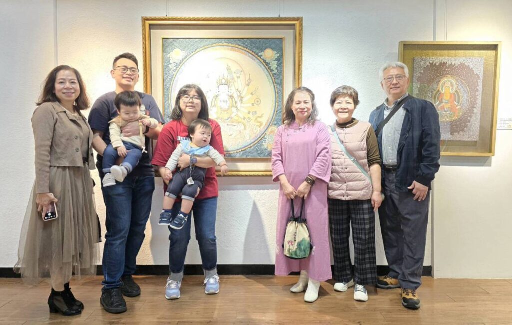 ▲來自桃園的知名佛像畫藝術家趙願心(右三)在她的展出作品「准提佛母」前與家人在展場合影留念。(記者 詹佳綺/攝)