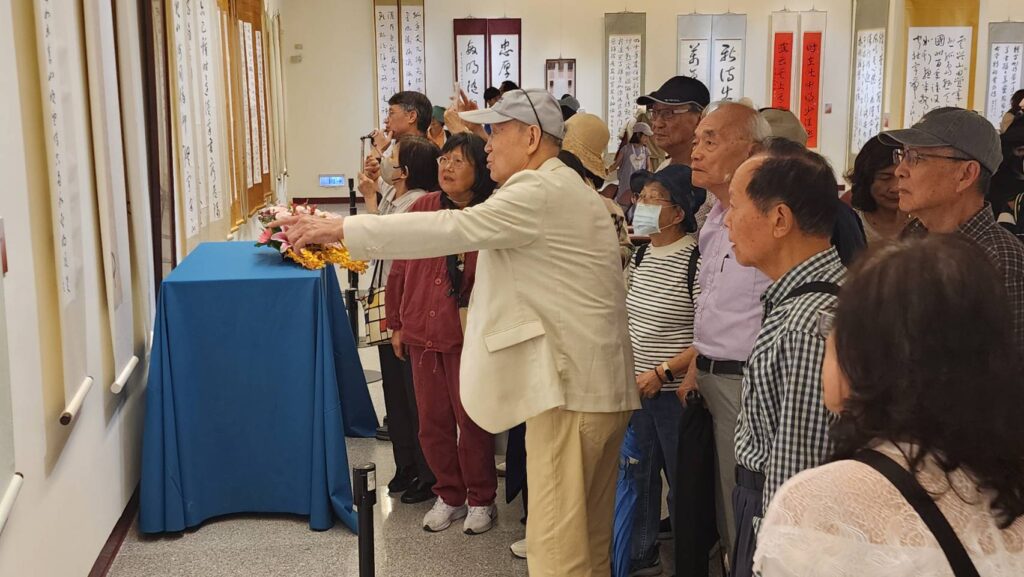 ▲知名書法家李貞吉教授（中）為出席開幕式活動的書友及學生們擔任展出作品的導覽，令觀者神情專注的體悟作品的文情深意，場面熱烈。（記者 詹佳綺/攝）