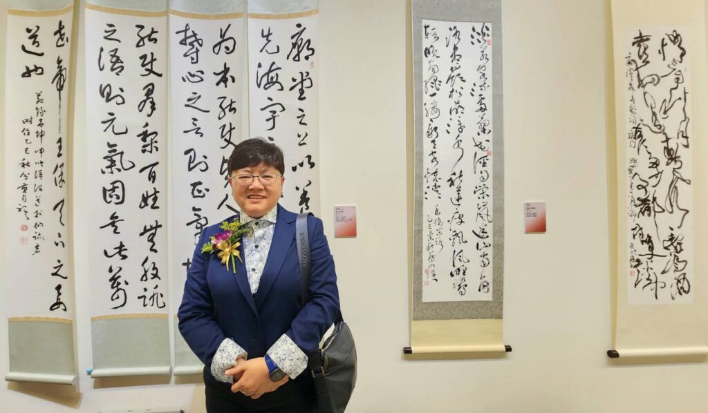 ▲中國標準草書學會理事長黃勻祺在國際書法展開幕式前，在所書寫展出的作品前表達對此年度大展所賦予的高度期待，強調此展呈現于右任大師的草書精神與個人風範，深具時代意義。（記者 詹佳綺/攝）