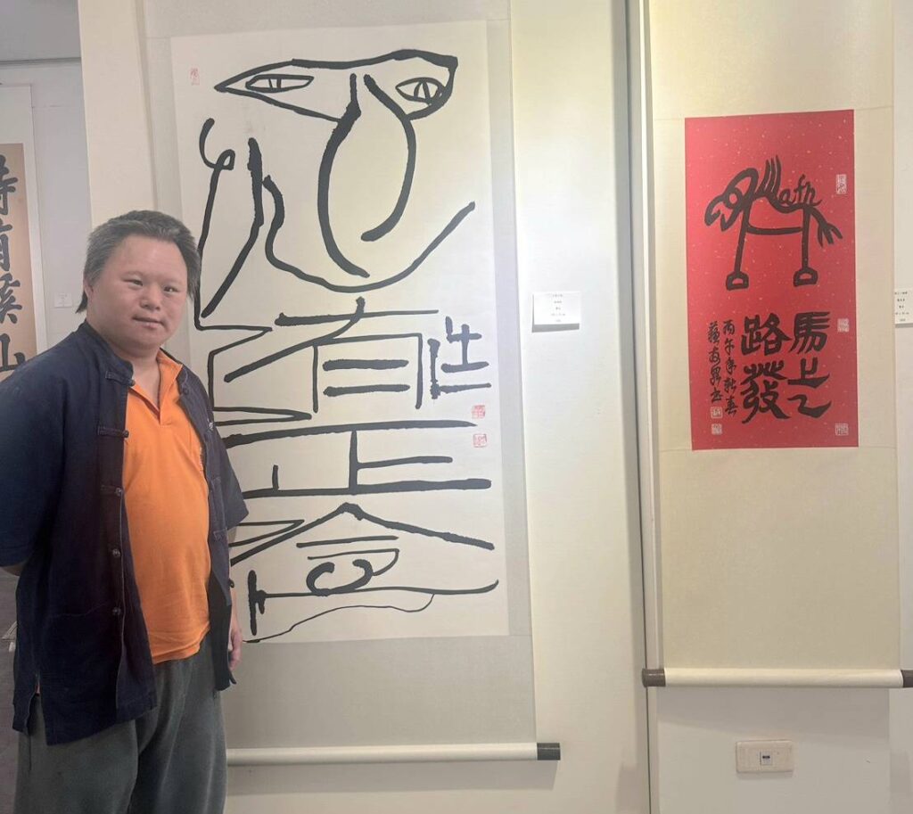 ▲年輕書畫創作藝術家林冠廷在他展出作品前留下合影紀念。（圖/林永發 提供）