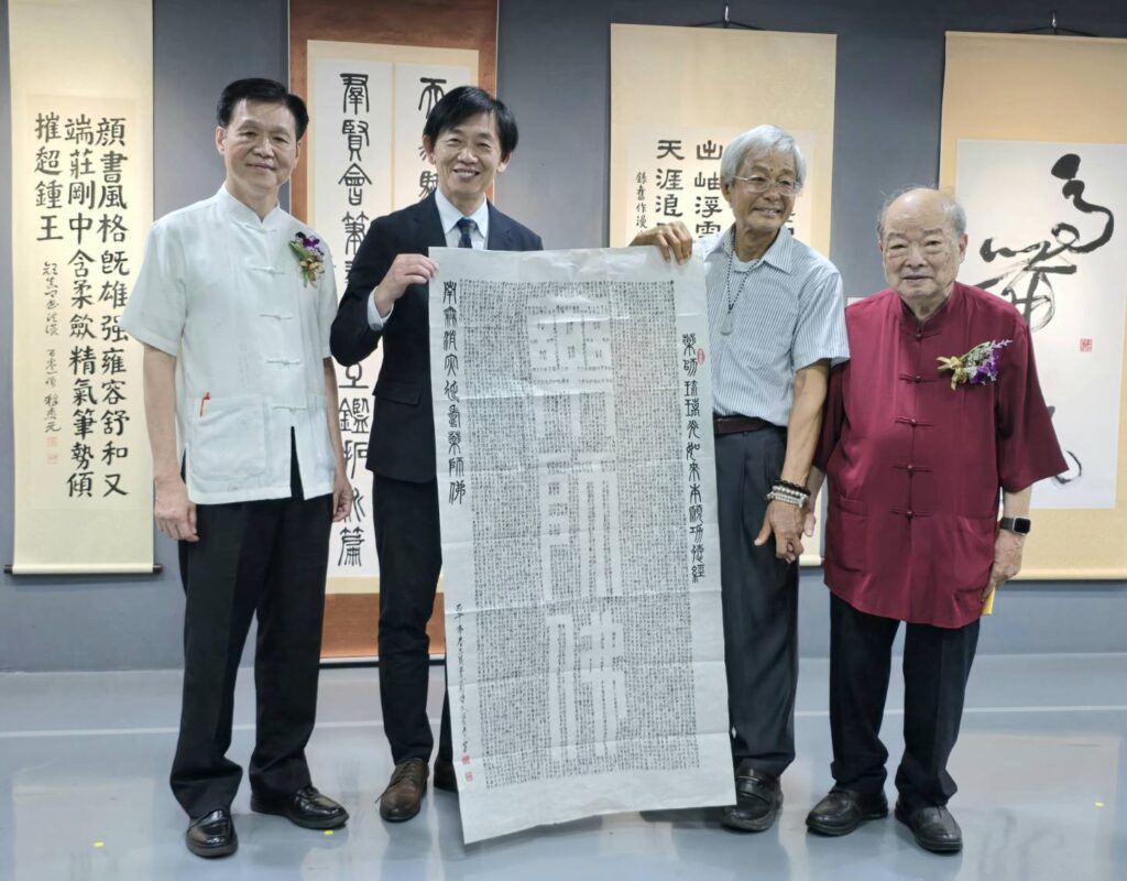 ▲退休教授劉博文（右二）致贈所書寫「藥師佛」經文墨寶給臺南市政府，由葉澤山副市長（左二）代表接受，並與陳銘鏡理事長（左一）諮詢委員何連成教授（右一）合影留念。（記者 詹佳綺/攝）