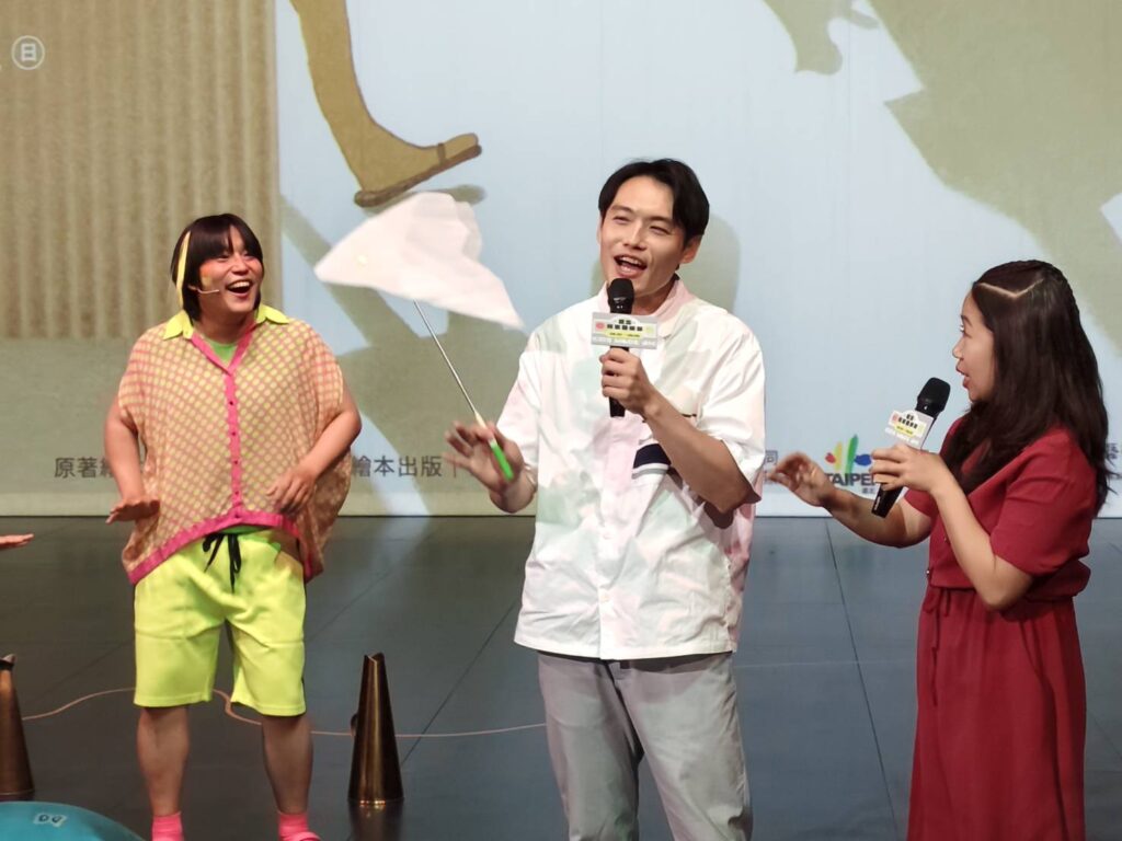 《小魚散步》主創者洪健藏(中)帶著道具接受主持人訪問。(記者 陳安婷/攝)