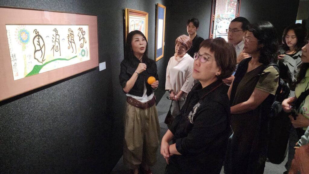 ▲蒙藏文化中心主任高玉珍(左)為出席活動的貴賓進行洪通作品的導覽,中為文化部政務次長王時思,仔細聆聽與觀賞展出之作品。(記者 辛澎祥/攝)