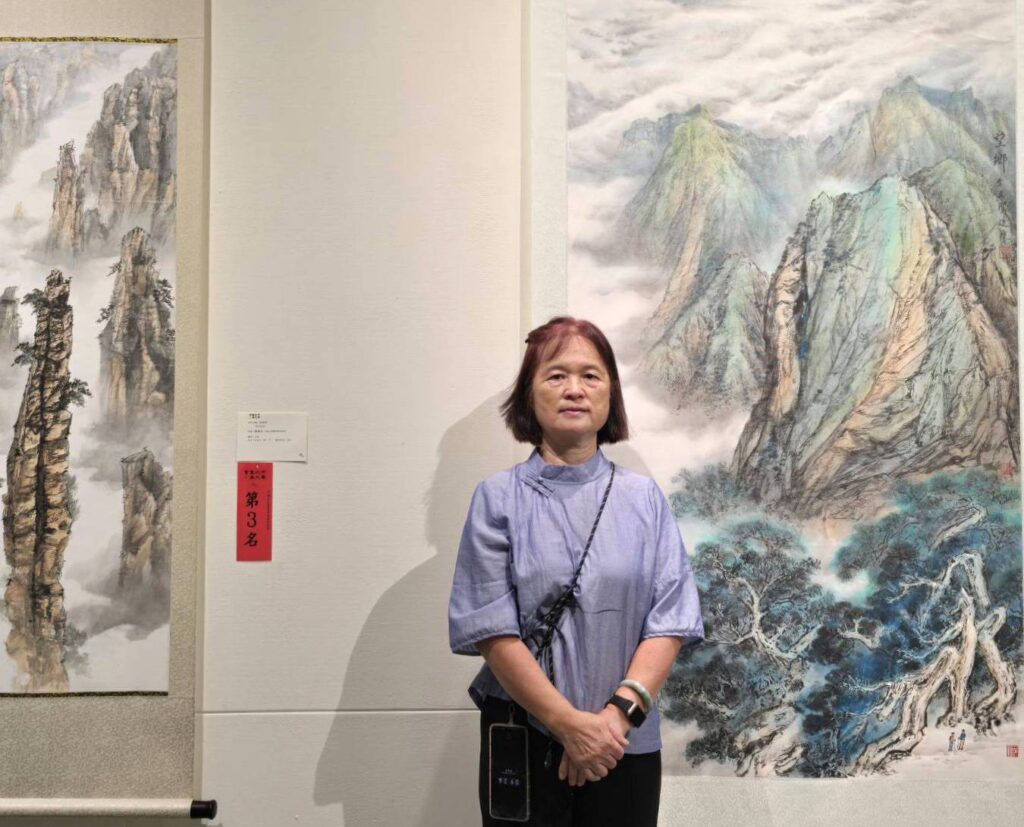 ▲中華九九書畫會理事長余真賢老師，在她所展出的作品前留影，彰顯出水墨創作的紮實技藝，相當受到好評。（記者 詹佳綺/攝）