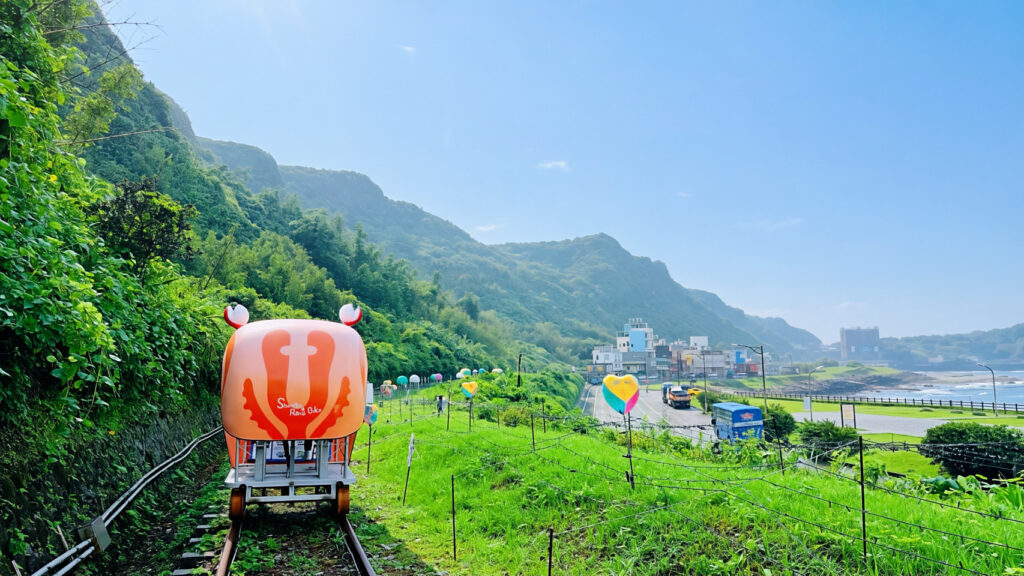 ▲旅客搭乘深澳鐵道自行車特製的螃蟹造型車依山傍海前行,沿途不僅能飽覽新北北海岸的翠綠山巒,更能將開闊的海景盡收眼底。(記者 新北觀旅局 提供)