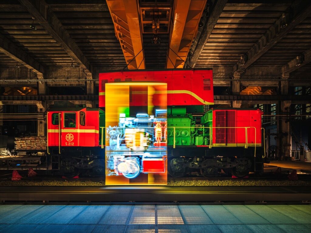 夜間燈光與展示影像映照S212號柴電機車，呈現車輛與工場展演結合的視覺效果。(圖/當若科技藝術提供)